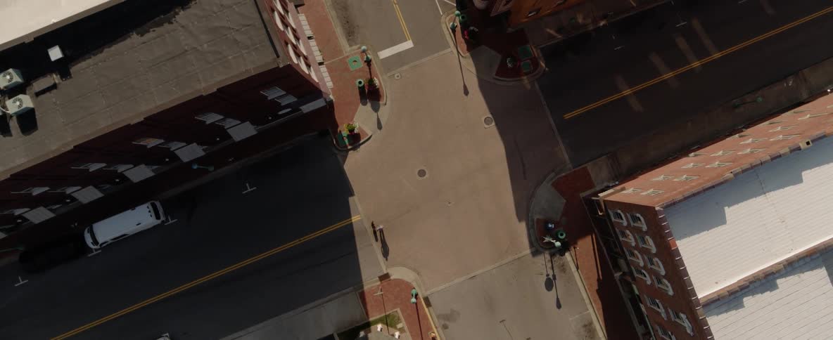 Car and pedestrian cross through intersection between four buildings