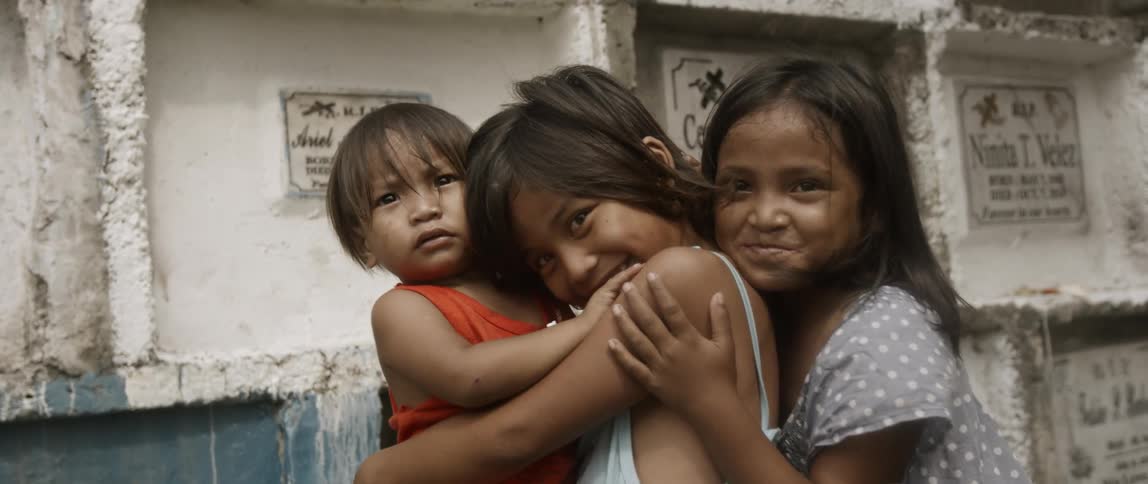 Children hug each other outside and smile