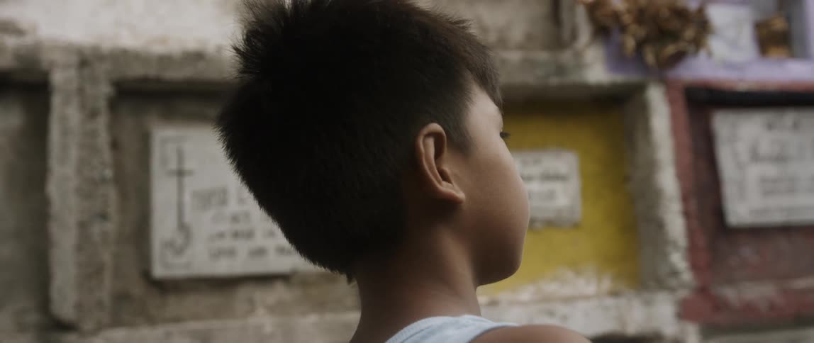 Asian boy with straight hair stands in front of the tablets in the daytime