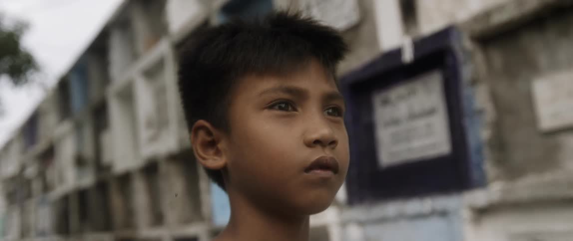 A young boy standing in a street near a wall