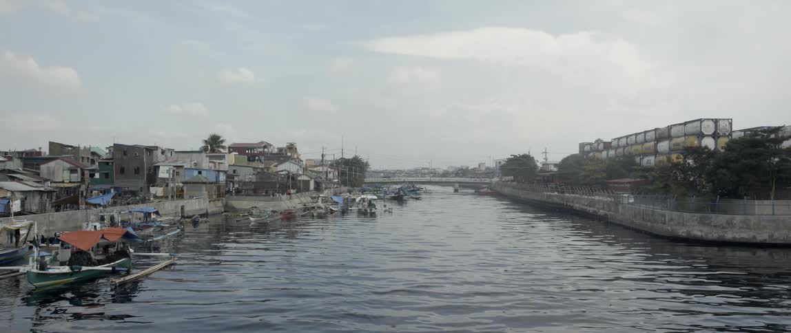 A river filled with small boats cuts through a town on a third world country