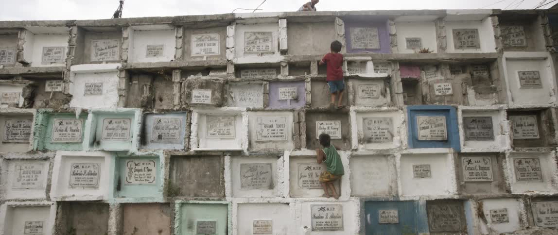 Children climb up the tall wall of graves