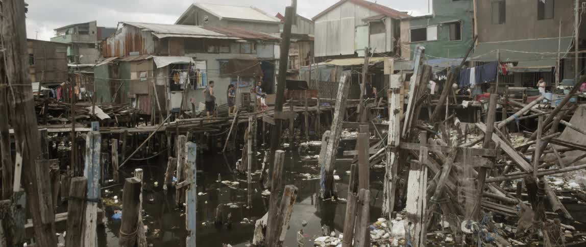 Shack houses surrounded by water with a lot of wood and trash