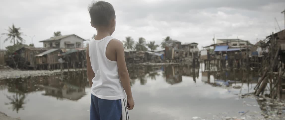 A boy looking out over a village built on stilts