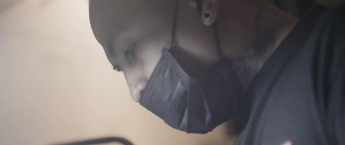 Tattoo artist in face mask tattooing on customer