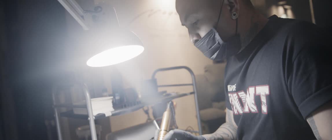 Tattoo artist drawing a tattoo on a mans leg