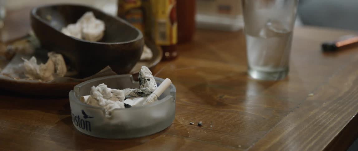 A smoking cigarette in a semi transparent ashtray