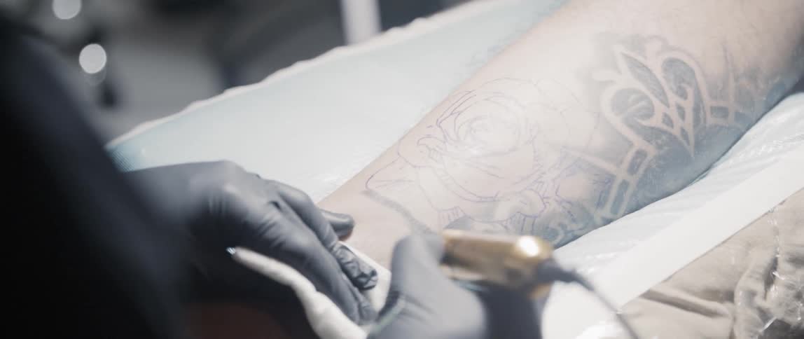 A tattoo artist working on an arm