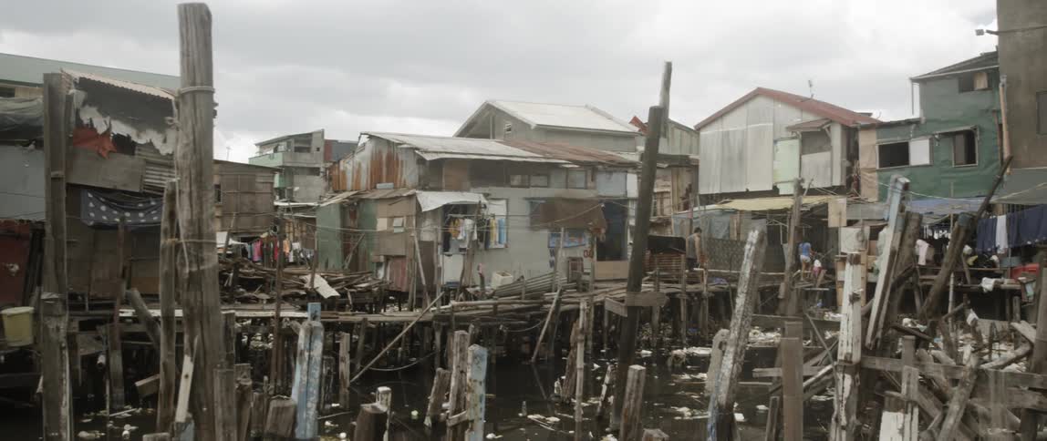People walk past the houses near the broken pier