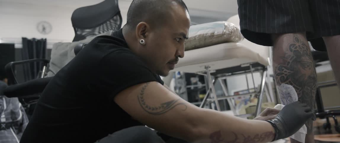 A tattoo artist puts a stencil on a mans leg