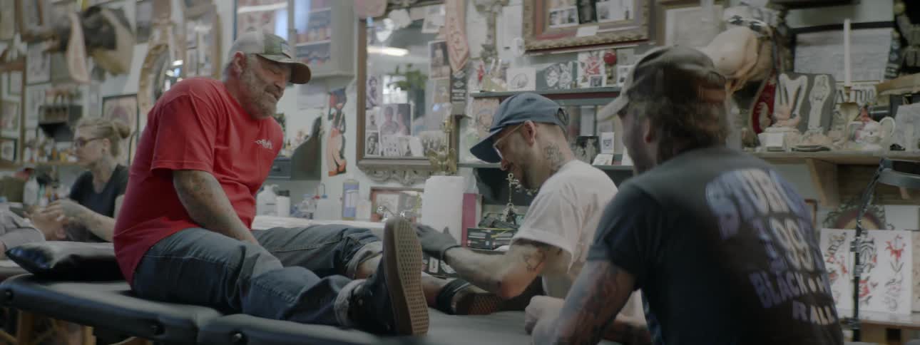 Tattooist is working on a mans leg