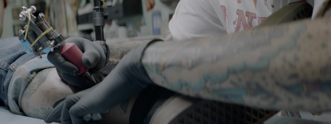 A tattoo artist is working on a customer