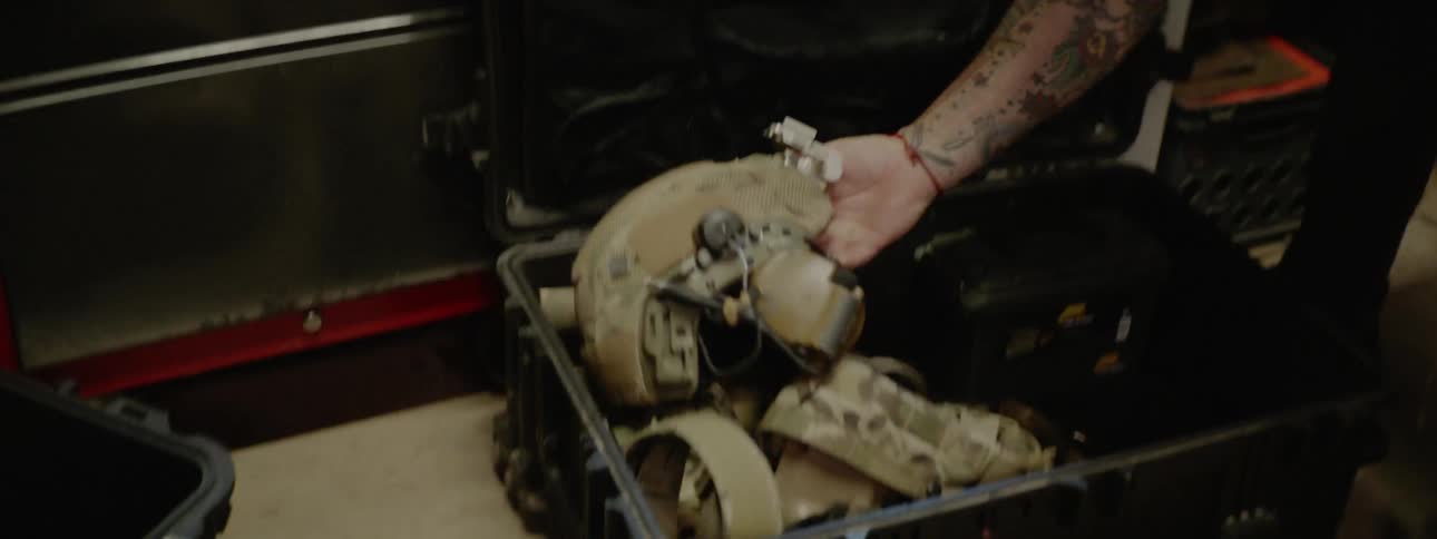 A man packs a container with a military helmet and gear