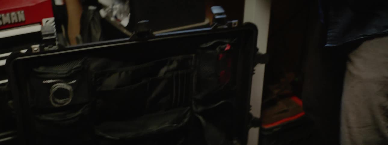 A man is wrapping up belts and putting them in a case