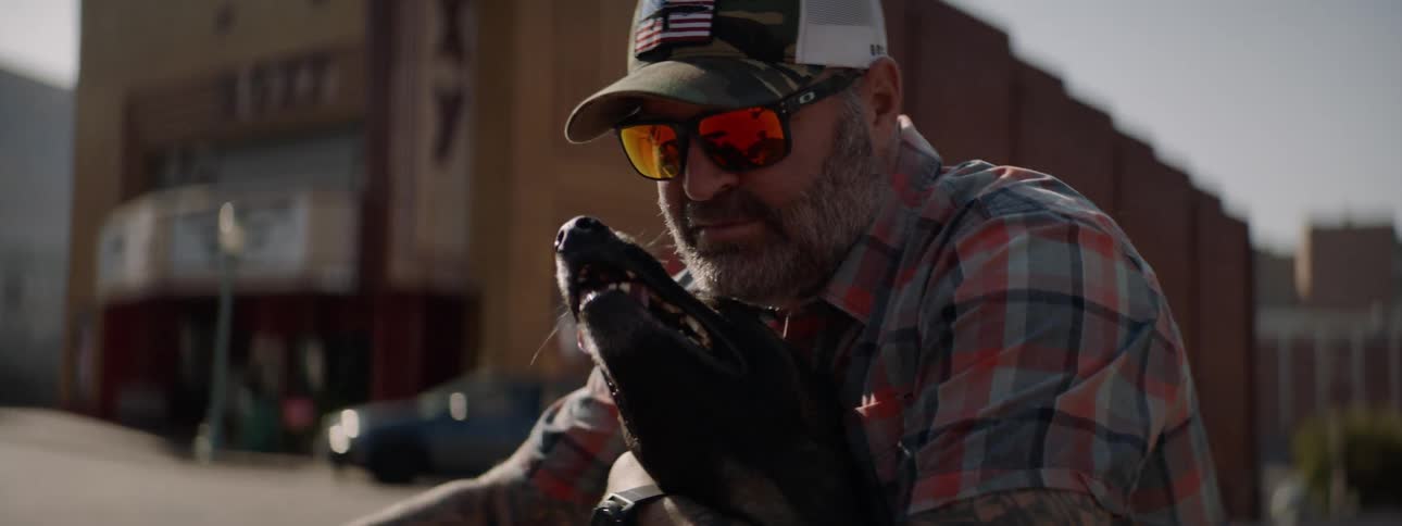 Man petting a happy black dog at a street corner