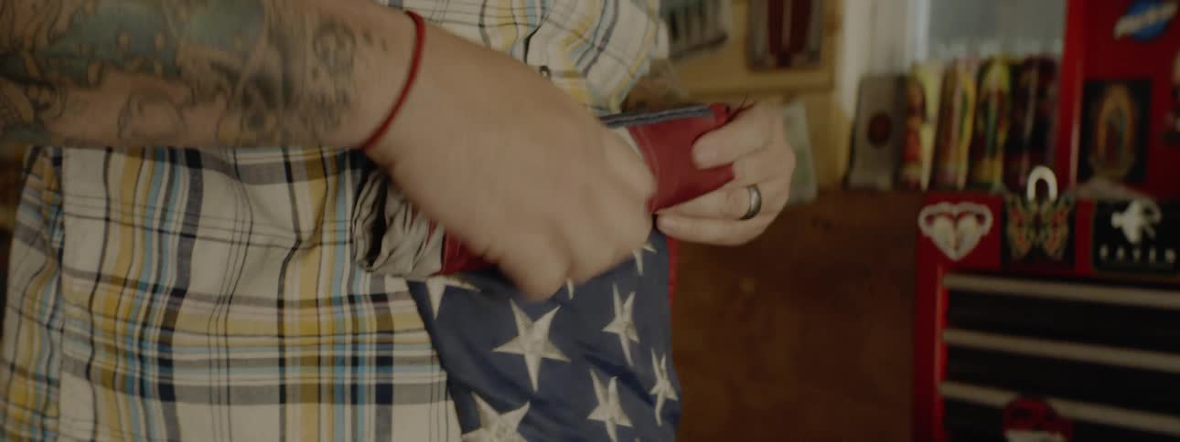 Man with tattooed arms rolls up american flag