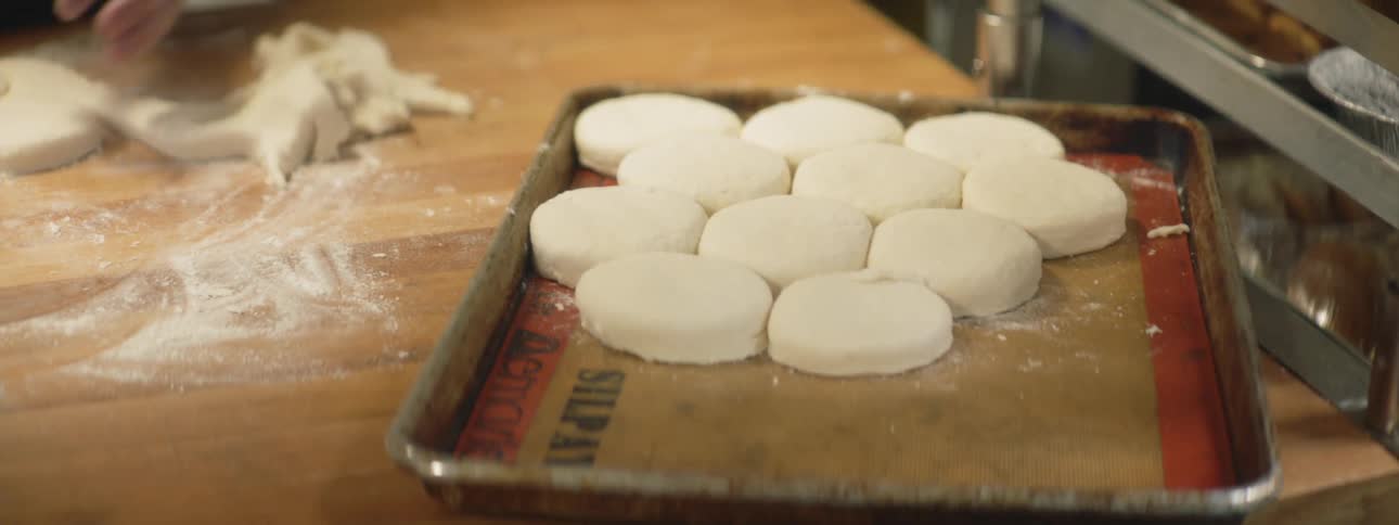 A person puts biscuits onto a cooking tray
