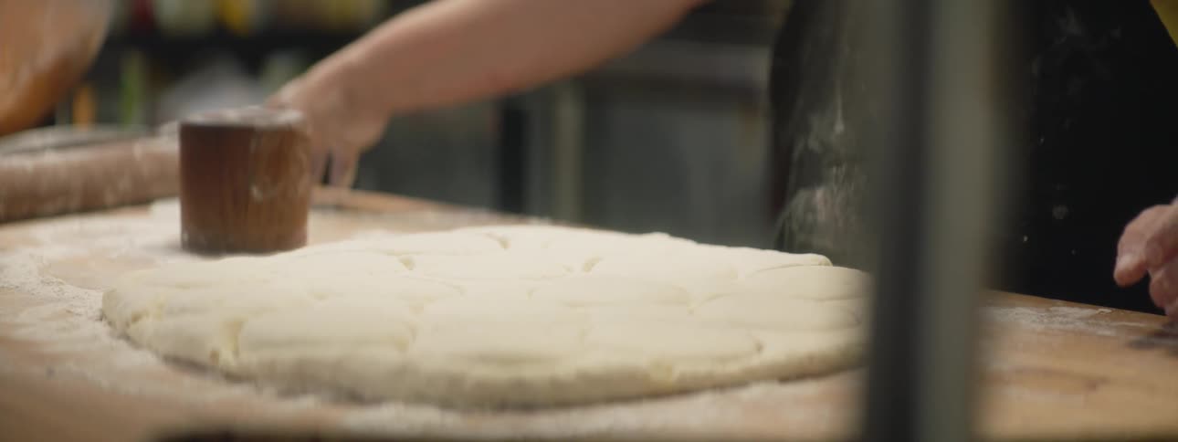 Woman wearing black t shirt cuts out dough which was laid on the table