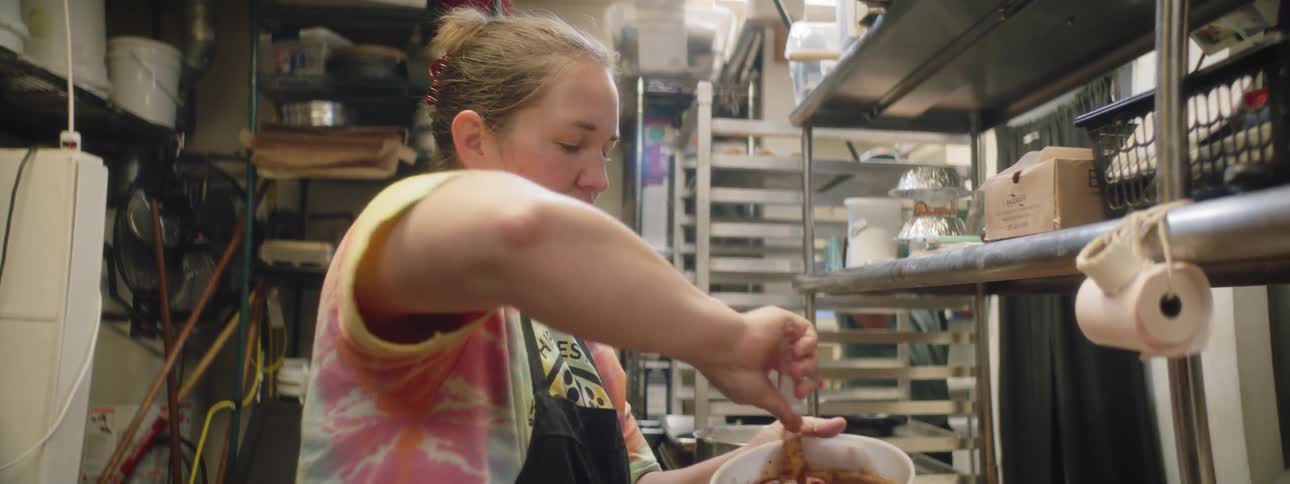 A woman mixes batter in a large container