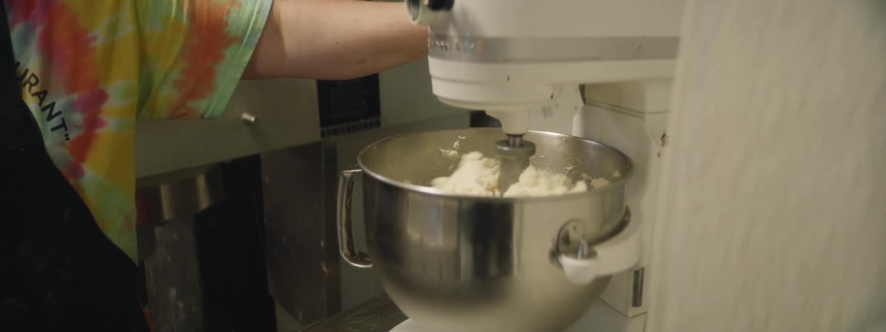 Person uses mixing machine in restaurant kitchen