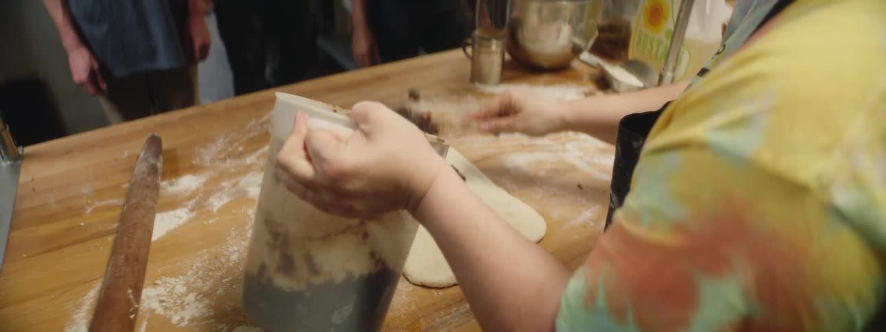 People are working in a kitchen with dough