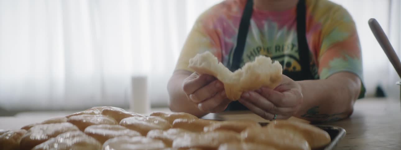 A person pulling apart a bun from a tray of buns on a table