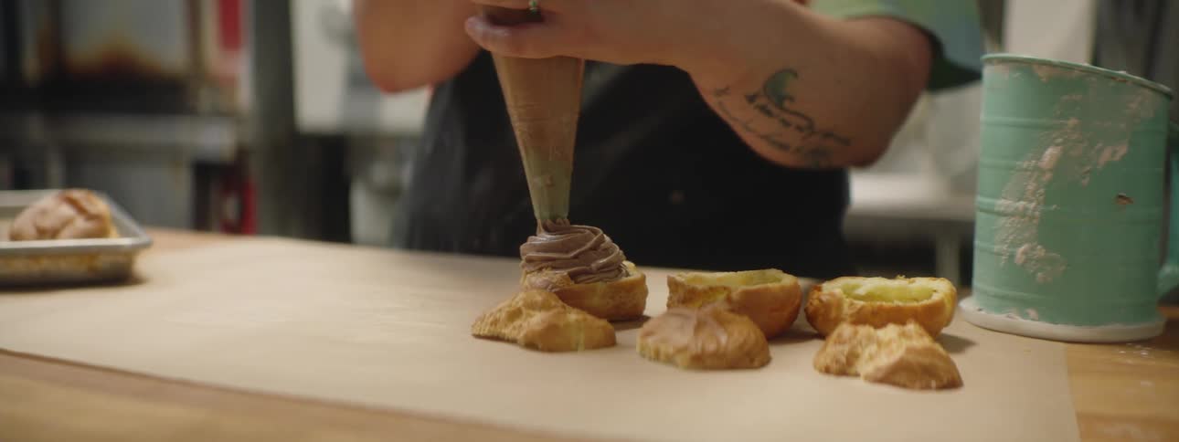 Baker fills choux pastry with cream