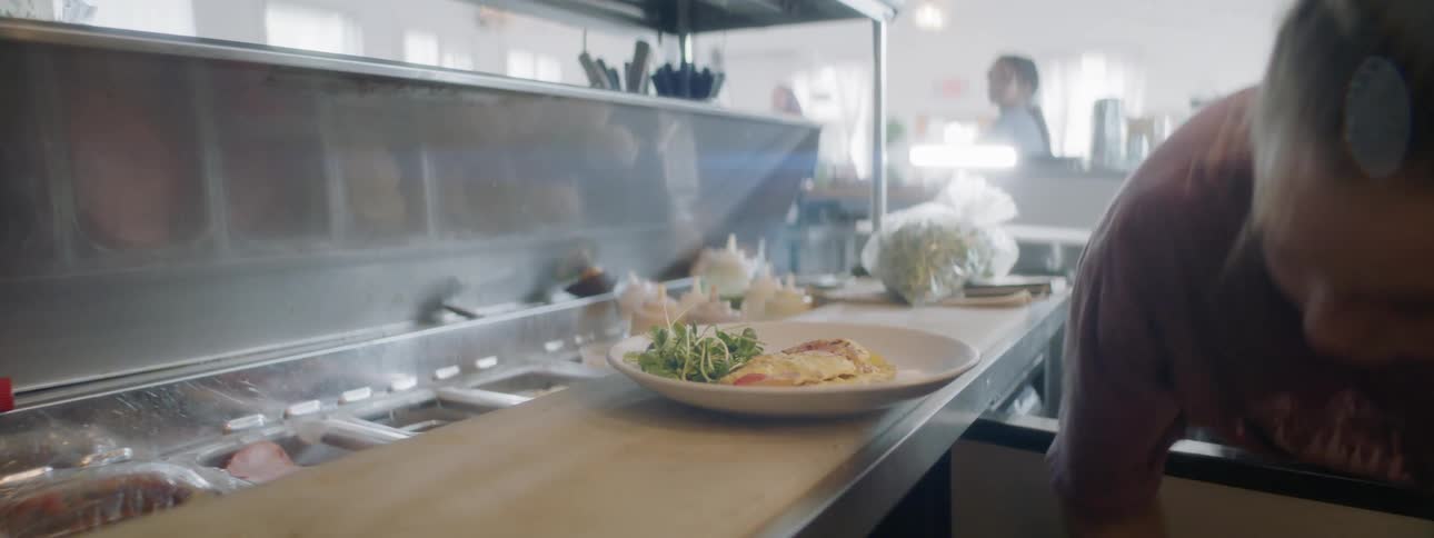 A woman prepares a plate of food in a restaurant