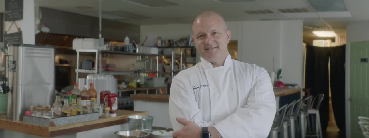 A chef posing in front of his kitchen