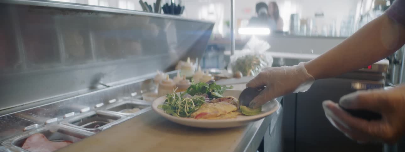 A woman puts avocado on a plate