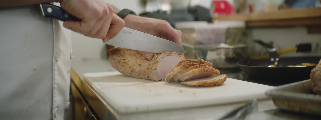 A chef cutting a piece of meat in a kitchen