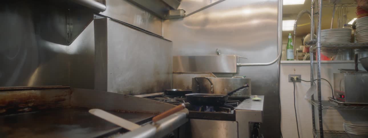 The camera looks towards a stove in a commercial kitchen