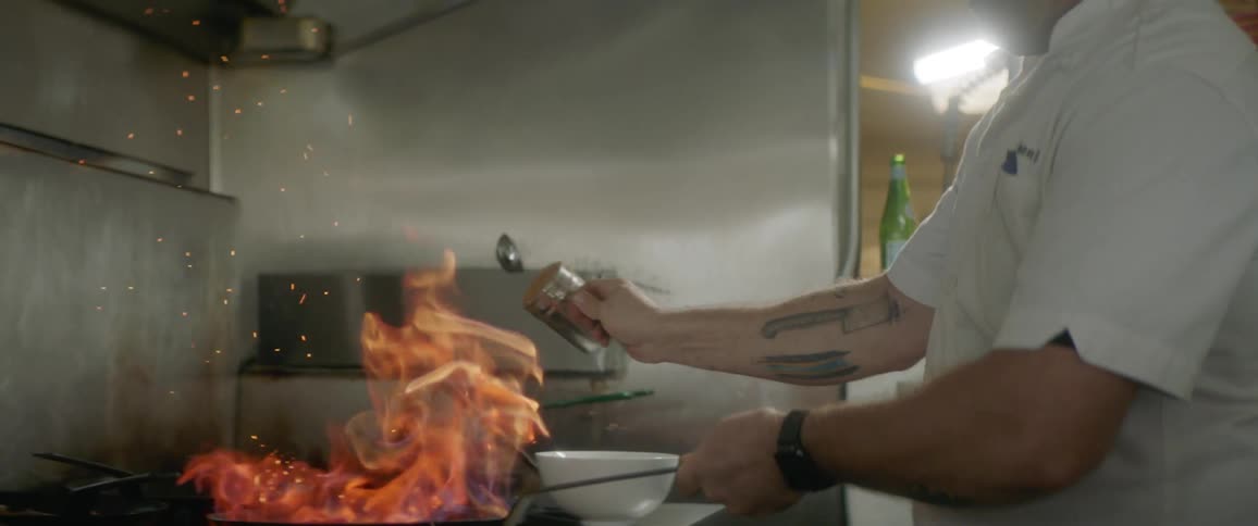 A man is cooking with a pan that is on fire