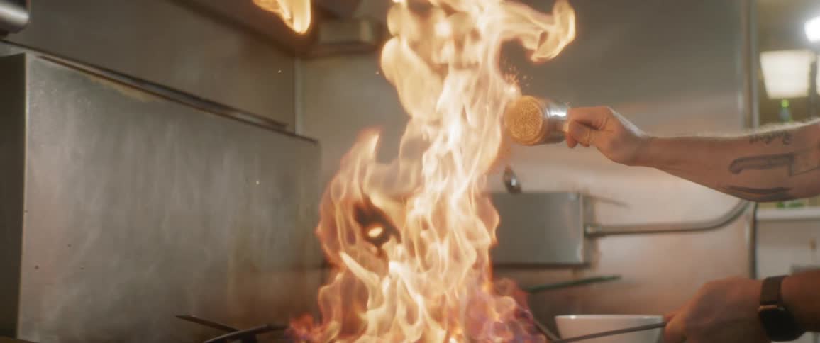 A man cooking on a flaming pan