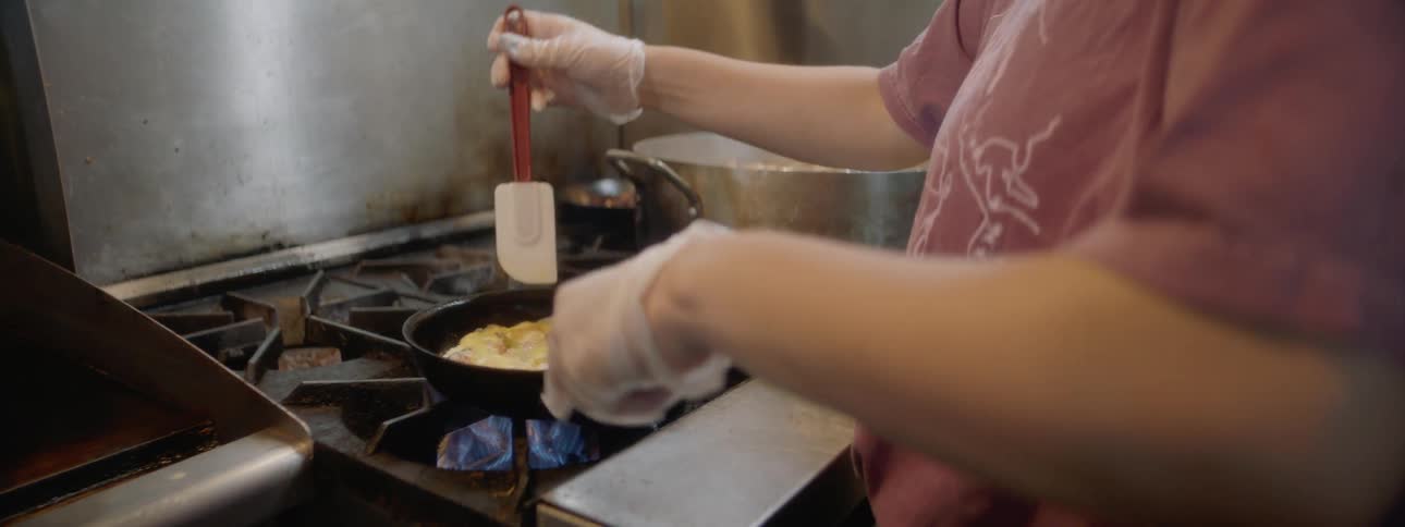 A woman cooking eggs in a kitchen inside a restaurant