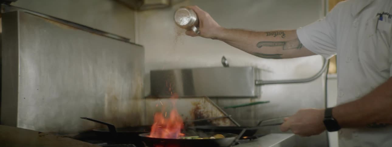 A man cooking with a pan in a kitchen