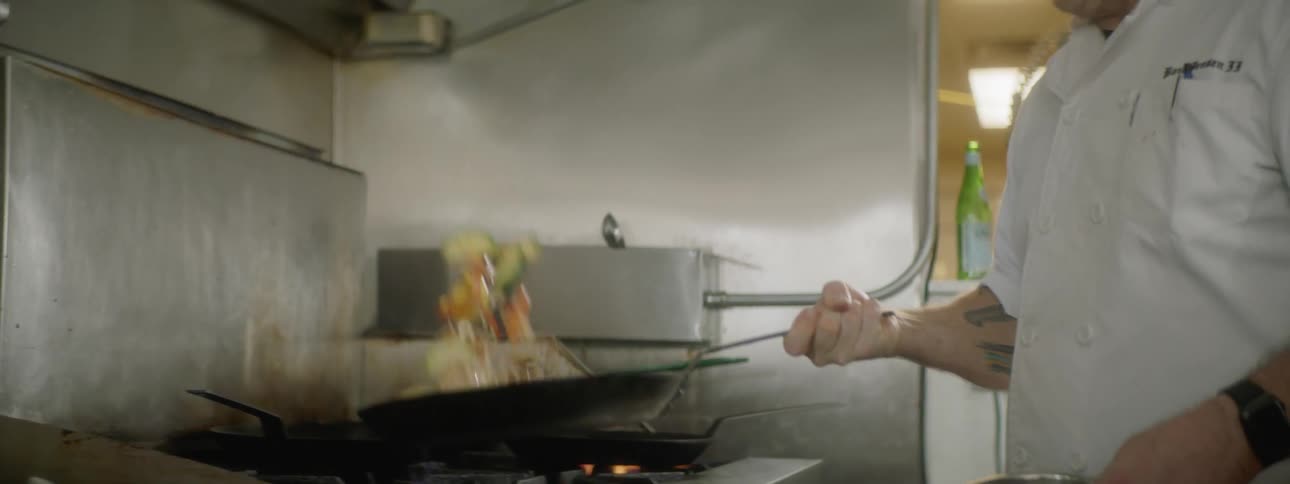 A young man flips food in a skillet