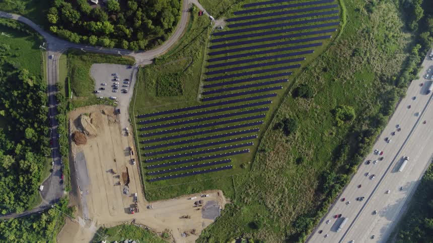 The vehicles travel on the highway past the solar farm
