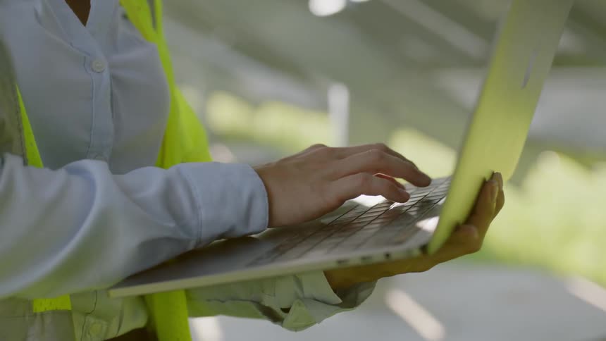 A woman is typing on her laptop at a work site