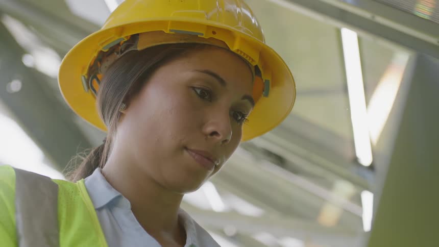 A woman is working near panels using a laptop