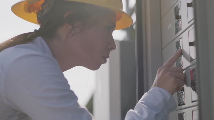 Woman in a yellow hard hat checks values on a set of gauges