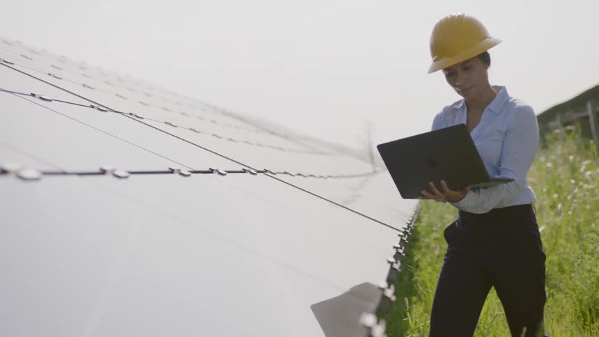 A woman in a hard hat uses a laptop