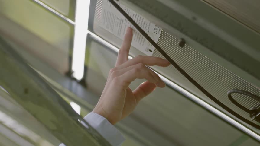 A woman in a hard hat reading a label on a window