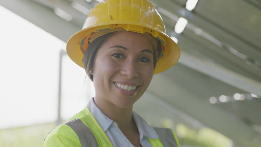 Woman on a hard hat looking at the camera and smiling