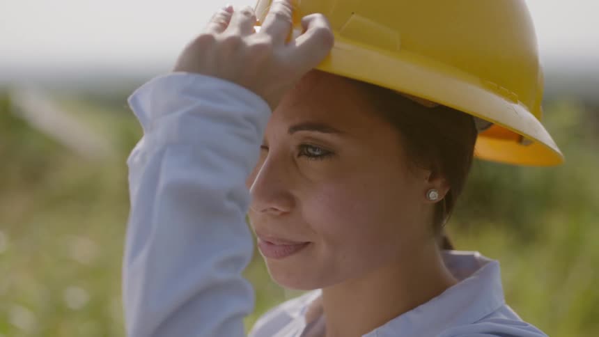 A woman puts on a hard hat and smiles