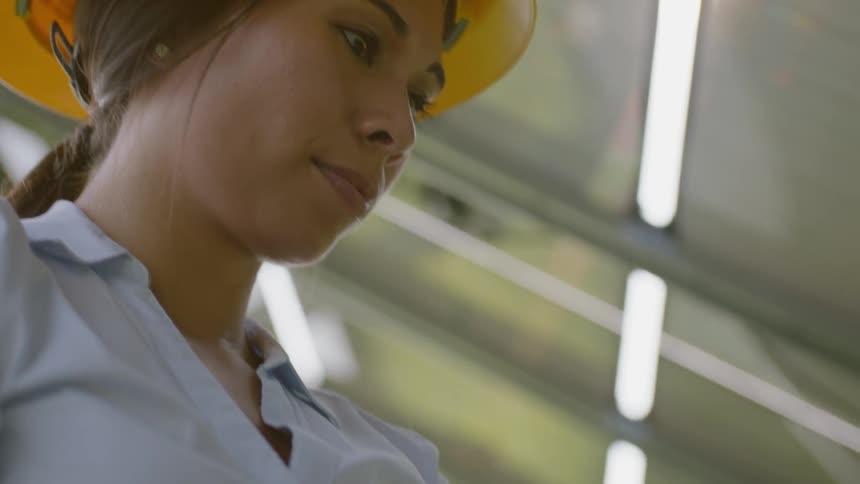 A woman in a hard hat is typing on a laptop