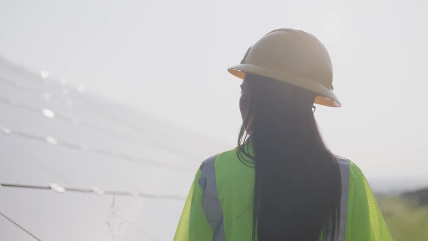 A black woman in a hardhat and safety vest inspecting a structure