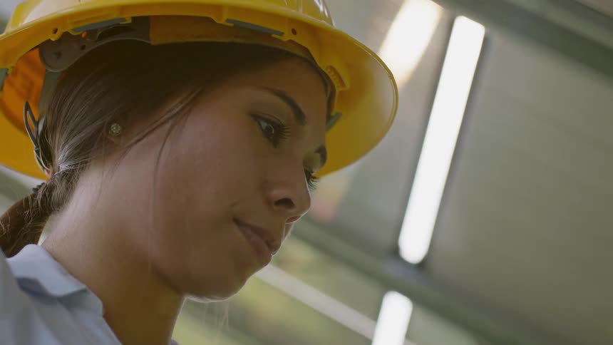 Woman wearing yellow hard hat under fluorescent lights
