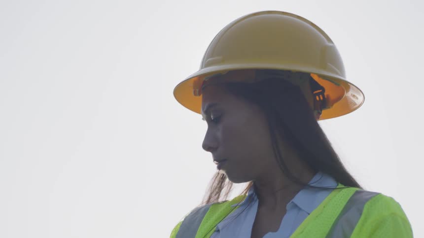 Woman on a hard hat inspection solar panels outside