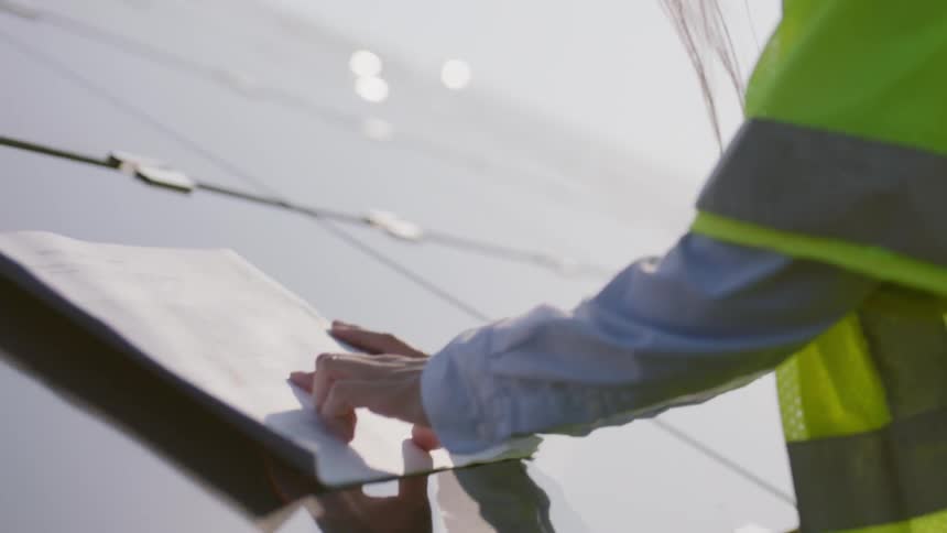 Woman architect wearing helmet checks on architects sketch on a sunny day